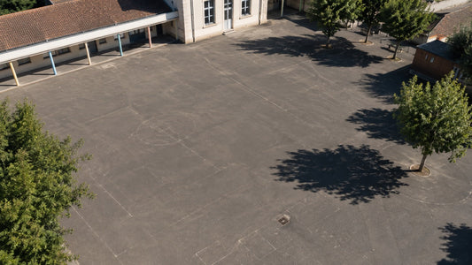 Cour d'école en bitume sombre vue en plongée sous le soleil d'été