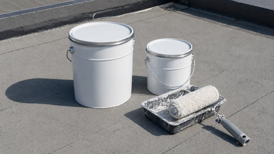 Deux pots de peinture de tailles différentes et un rouleau posés sur une toiture-terrasse
